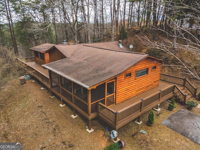 exterior space with roof with shingles, faux log siding, and a deck