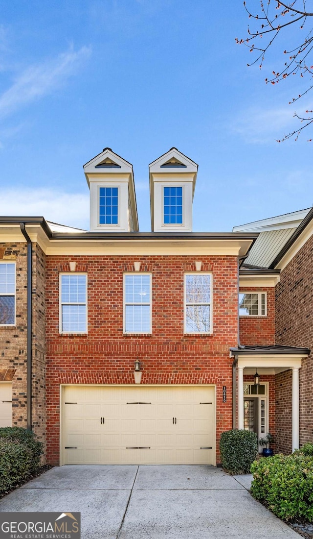 view of front of property featuring a garage, concrete driveway, and brick siding