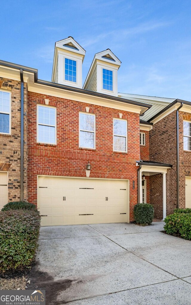 multi unit property featuring brick siding, driveway, and an attached garage