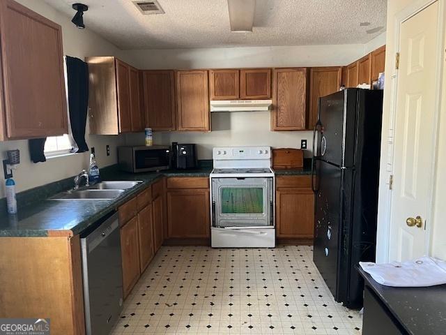 kitchen with dark countertops, visible vents, appliances with stainless steel finishes, a sink, and under cabinet range hood