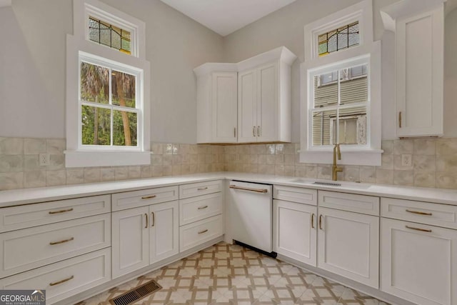 kitchen featuring light floors, white dishwasher, a sink, and light countertops