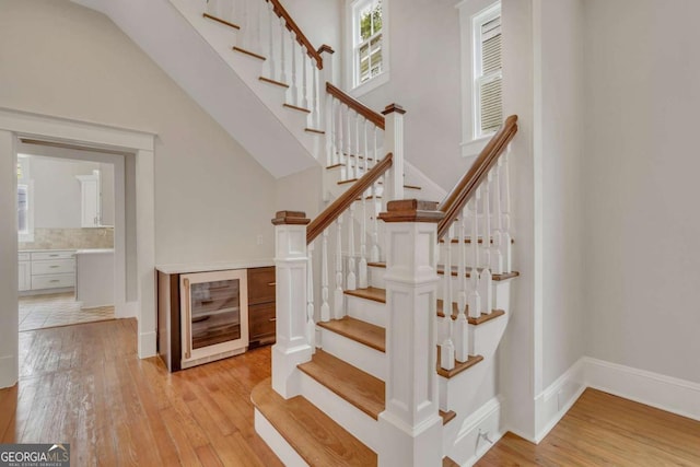 stairway with a towering ceiling, hardwood / wood-style flooring, and baseboards