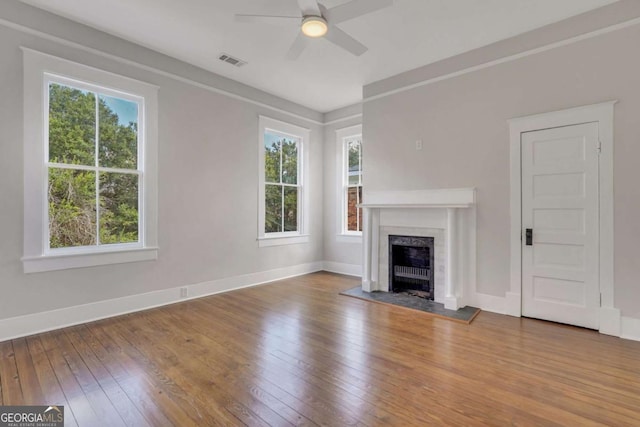 unfurnished living room featuring a wealth of natural light, hardwood / wood-style flooring, a fireplace, and visible vents