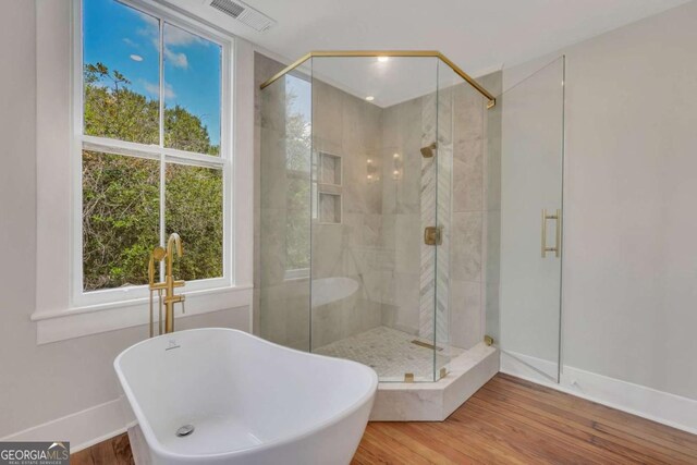 bathroom with a soaking tub, visible vents, a shower stall, and wood finished floors