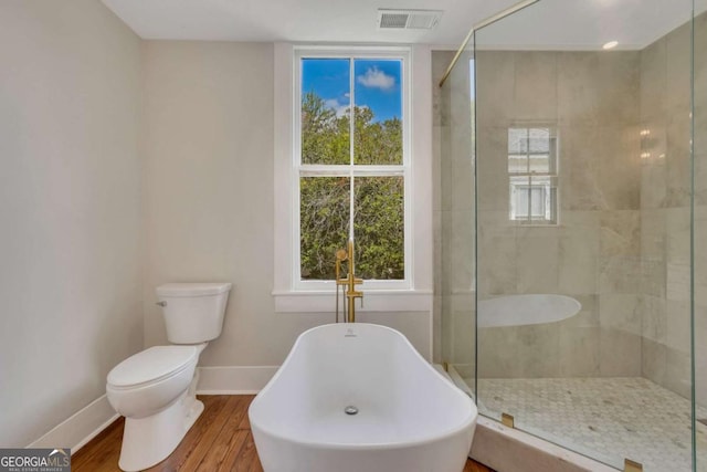 bathroom featuring visible vents, toilet, a shower stall, wood finished floors, and baseboards