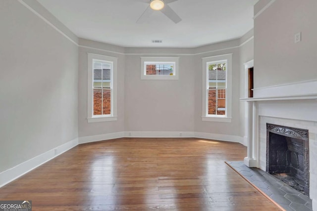 unfurnished living room with baseboards, visible vents, a fireplace, and hardwood / wood-style floors