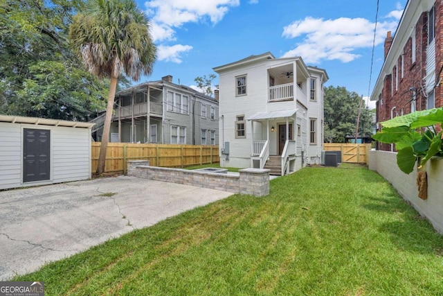 back of house with a ceiling fan, central AC, a balcony, a fenced backyard, and an outdoor structure