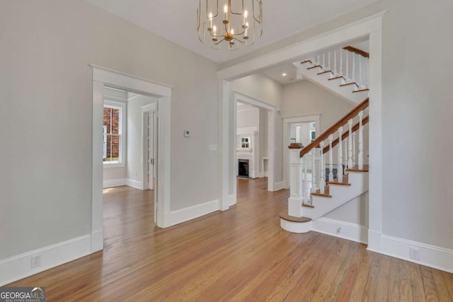 entryway featuring light wood finished floors, baseboards, a fireplace, and stairway