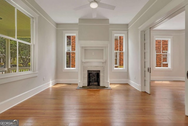 unfurnished living room with plenty of natural light, wood-type flooring, a fireplace, and baseboards