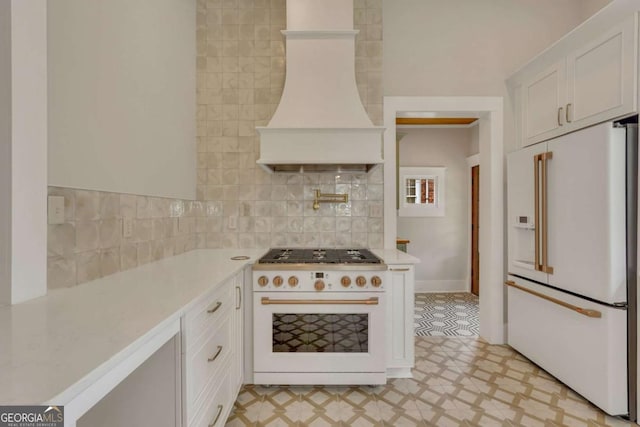 kitchen featuring light floors, light countertops, custom range hood, white cabinetry, and white appliances