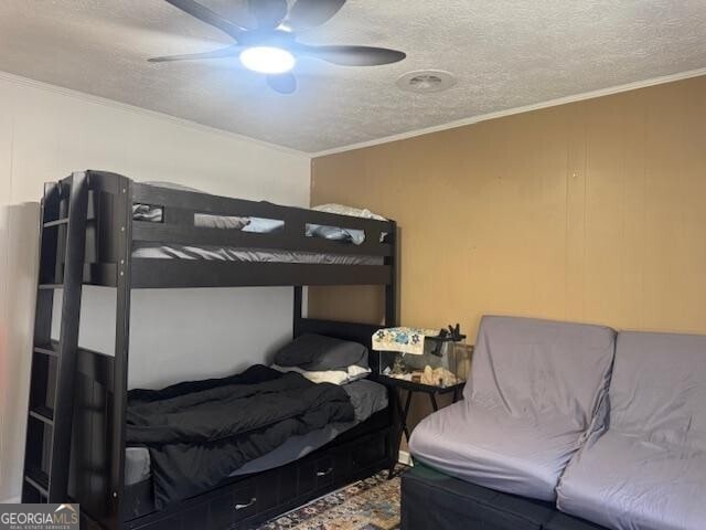 bedroom with a textured ceiling, ceiling fan, and ornamental molding