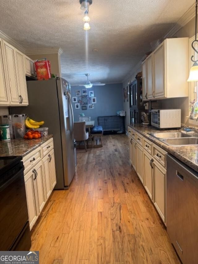 kitchen featuring light wood-style flooring, a sink, appliances with stainless steel finishes, a textured ceiling, and crown molding