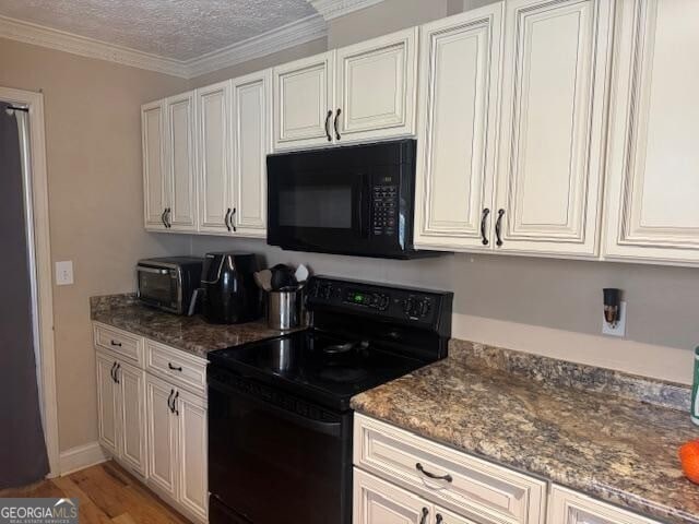 kitchen with light wood-type flooring, black appliances, ornamental molding, a textured ceiling, and dark stone counters