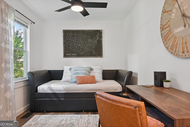 living area featuring baseboards, a healthy amount of sunlight, wood finished floors, and a ceiling fan