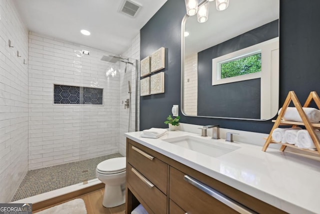 full bath featuring vanity, a shower stall, toilet, and visible vents