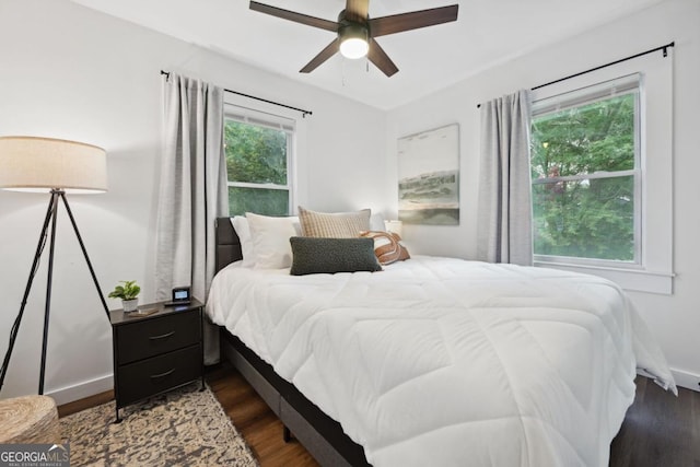 bedroom with dark wood-type flooring, multiple windows, baseboards, and ceiling fan