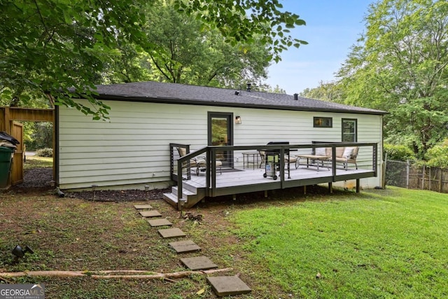 back of property with a deck, fence, and a lawn