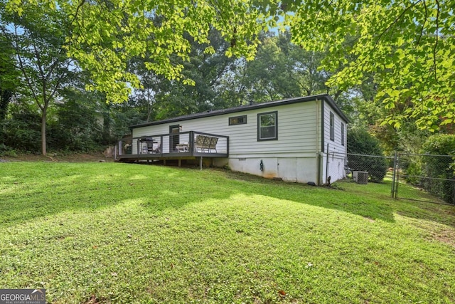 rear view of house with a gate, a yard, a wooden deck, and fence