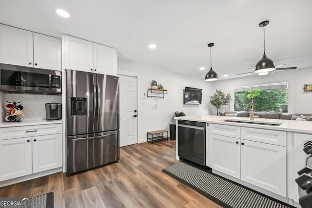 kitchen with dark wood finished floors, a sink, stainless steel appliances, light countertops, and white cabinetry