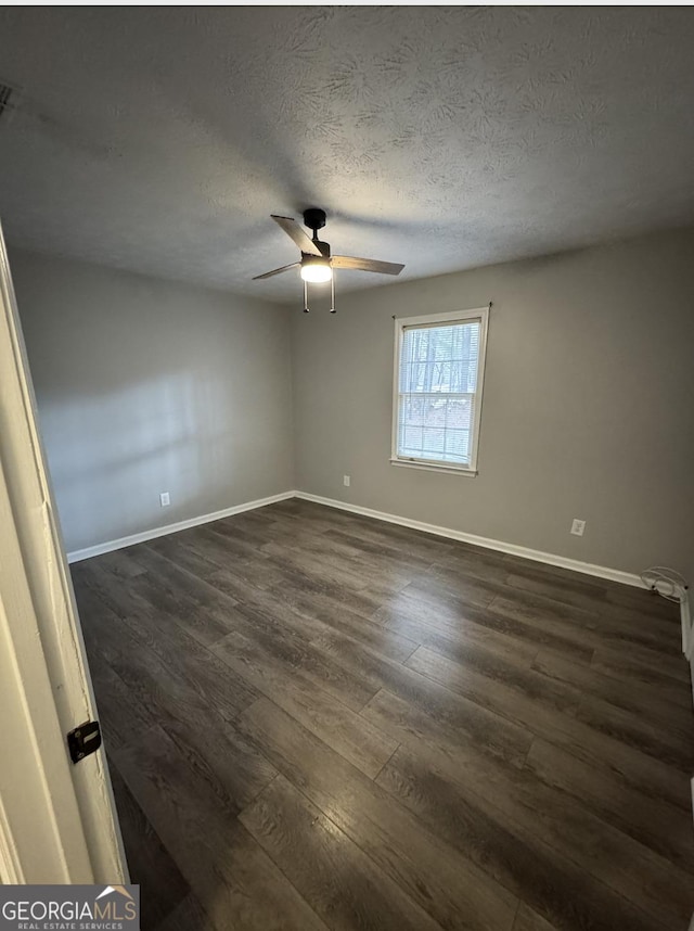 unfurnished room with dark wood-style flooring, ceiling fan, a textured ceiling, and baseboards