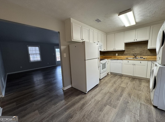 kitchen featuring white appliances, wood finished floors, a sink, visible vents, and white cabinets