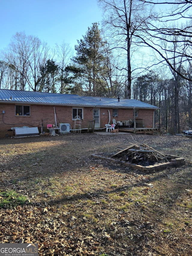 rear view of house with metal roof, brick siding, and a standing seam roof