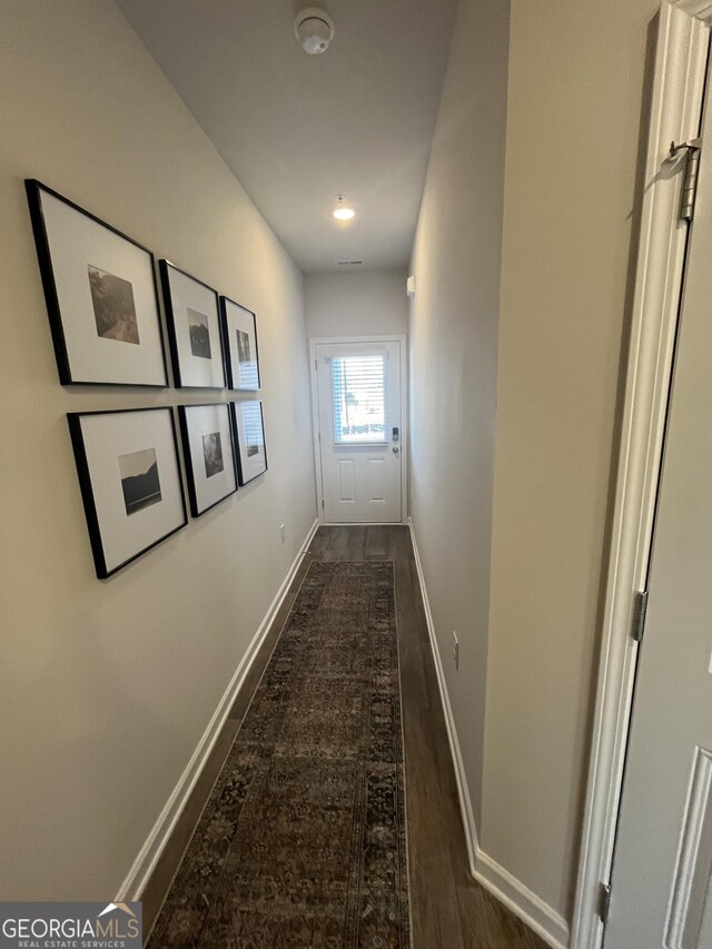 hall featuring attic access and dark carpet