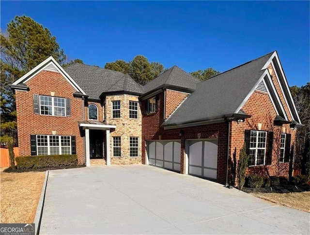 view of front of property featuring a garage, brick siding, a shingled roof, driveway, and stone siding