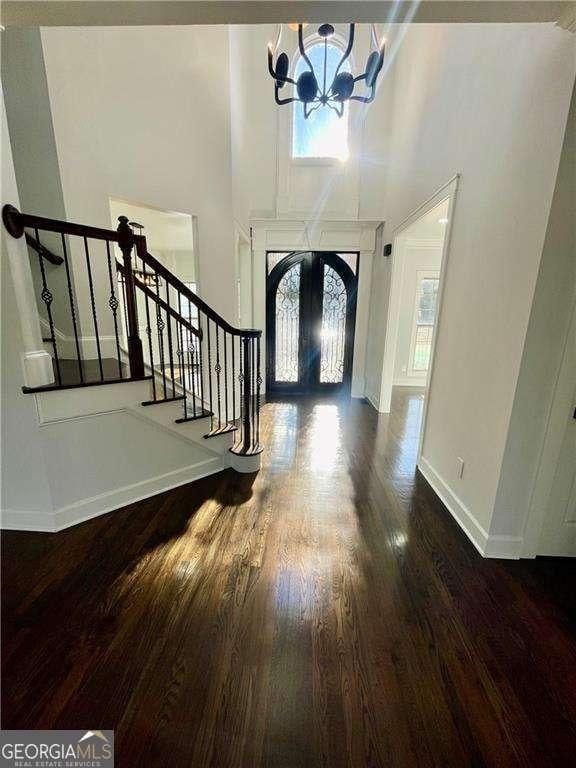 entrance foyer featuring baseboards, wood finished floors, stairs, french doors, and a notable chandelier