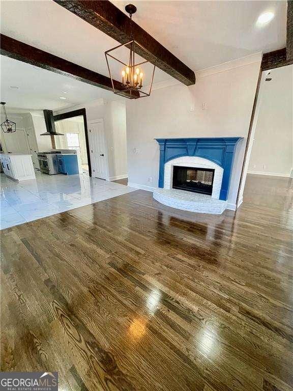 3499 Lake Mill Rd, Buford, GA 30519 - unfurnished living room with beam ceiling, wood finished floors, baseboards, a chandelier, and a fireplace