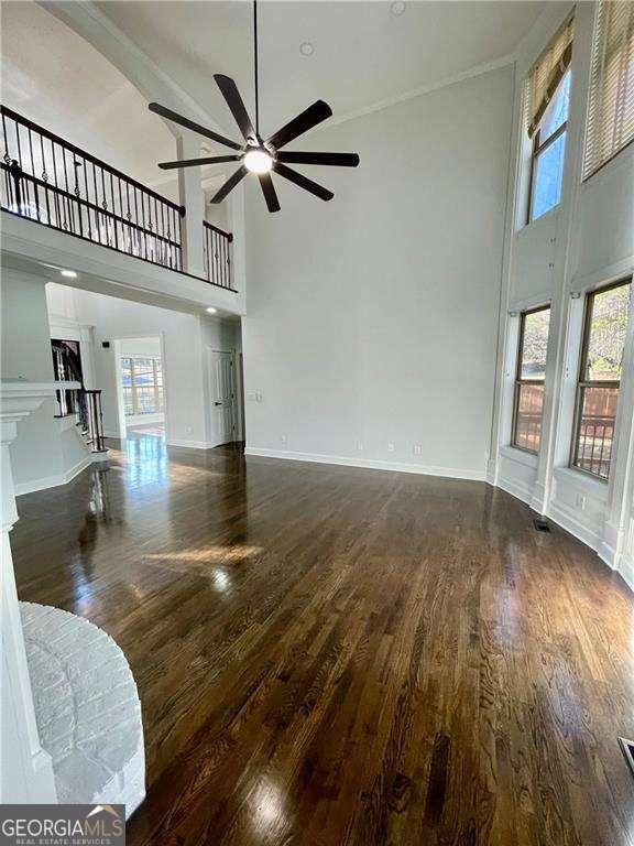 living room with dark wood-style flooring, baseboards, and a high ceiling