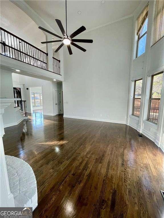 3499 Lake Mill Rd, Buford, GA 30519 - unfurnished living room featuring a high ceiling, dark wood-style flooring, healthy amount of natural light, ceiling fan, and baseboards