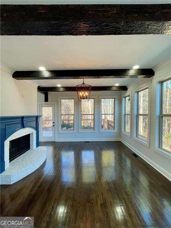 3499 Lake Mill Rd, Buford, GA 30519 - unfurnished living room featuring wood finished floors, a fireplace, beam ceiling, and a chandelier
