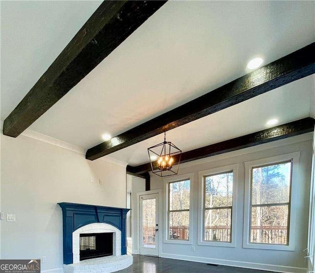 interior details with visible vents, baseboards, beamed ceiling, a brick fireplace, and a notable chandelier