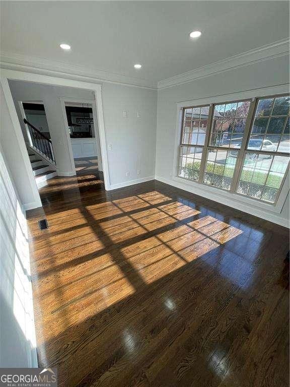 spare room with crown molding, baseboards, dark wood-style flooring, and recessed lighting