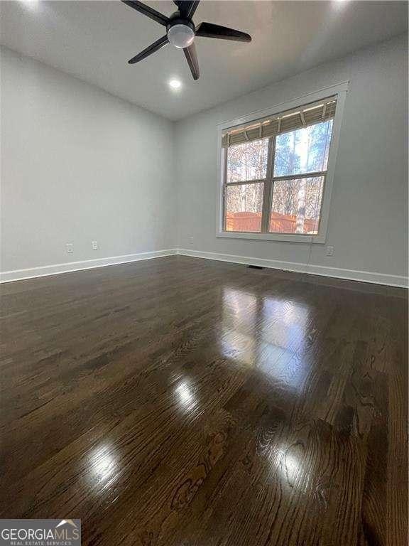 empty room featuring dark wood-style floors, ceiling fan, and baseboards