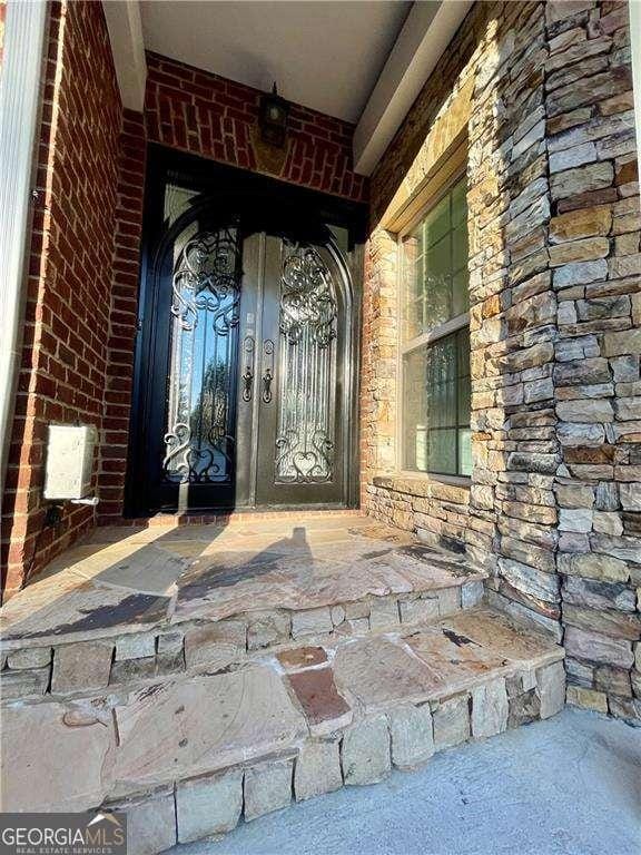 entrance to property featuring stone siding and brick siding