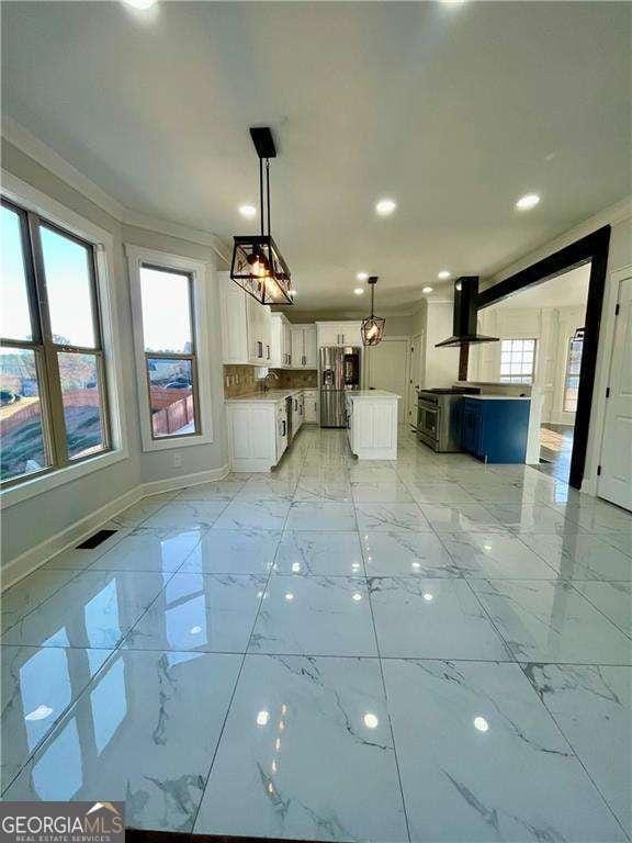 kitchen featuring range hood, marble finish floor, white cabinets, and plenty of natural light