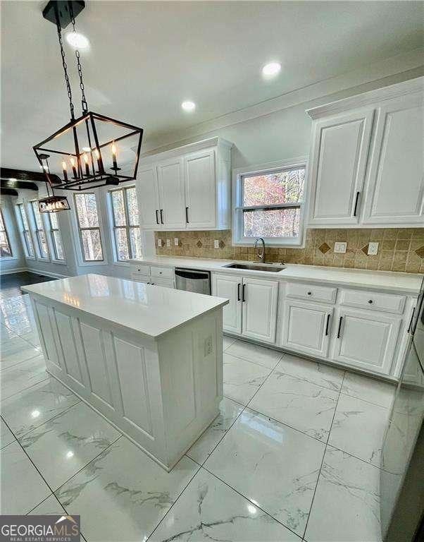 kitchen featuring dishwasher, marble finish floor, light countertops, white cabinetry, and a sink