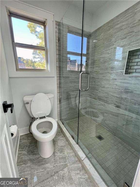 full bathroom featuring a stall shower, toilet, and baseboards