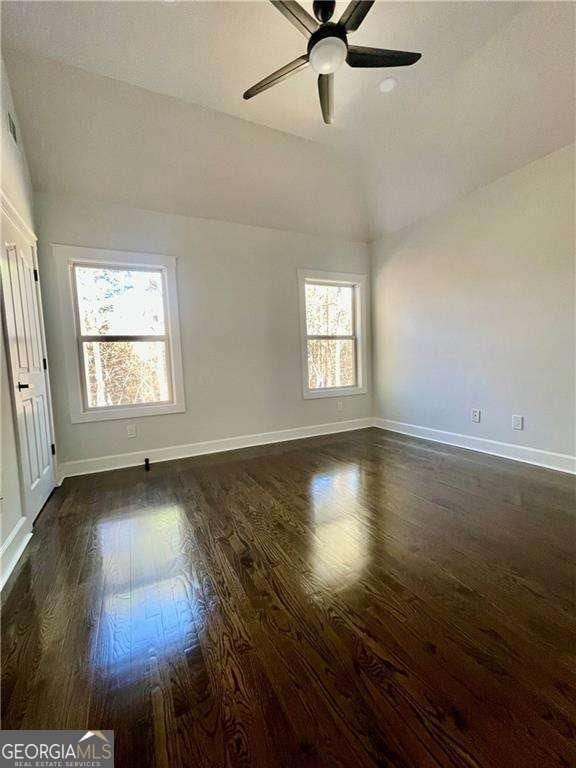 unfurnished room featuring baseboards, vaulted ceiling, and wood finished floors