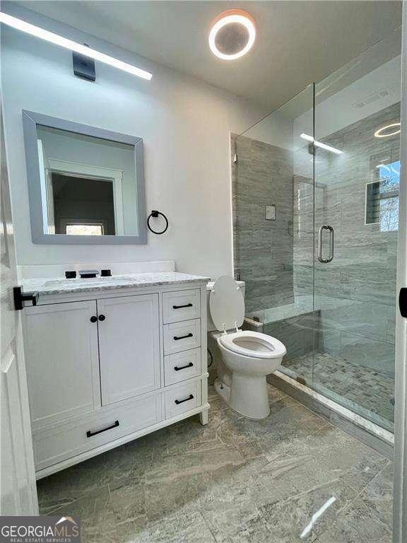 full bathroom featuring toilet, a shower stall, and vanity