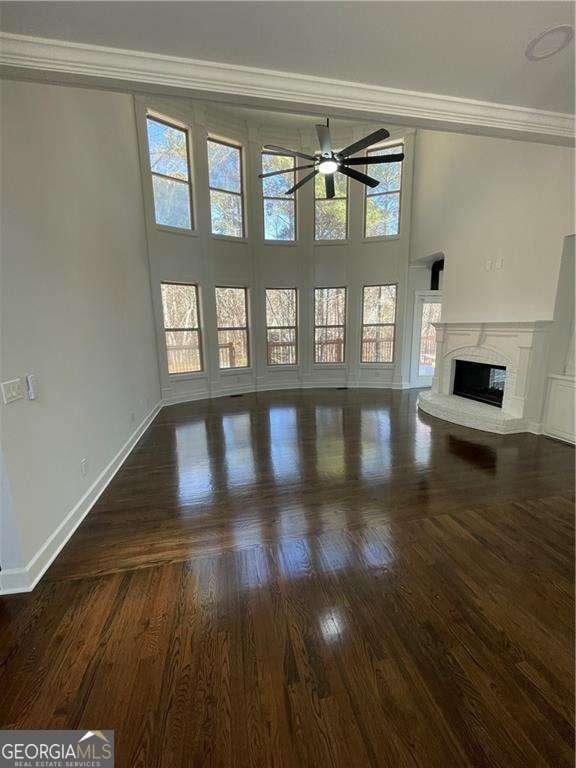 3499 Lake Mill Rd, Buford, GA 30519 - unfurnished living room with ceiling fan, ornamental molding, a fireplace with raised hearth, baseboards, and wood finished floors