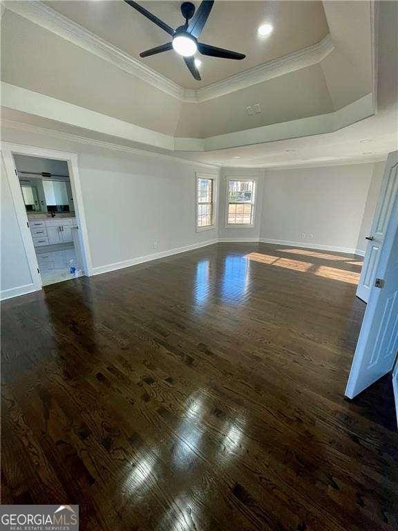 interior space featuring baseboards, a raised ceiling, crown molding, and wood finished floors