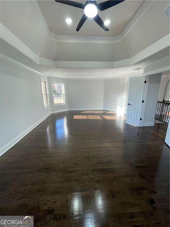 unfurnished room featuring baseboards, a tray ceiling, wood finished floors, and crown molding