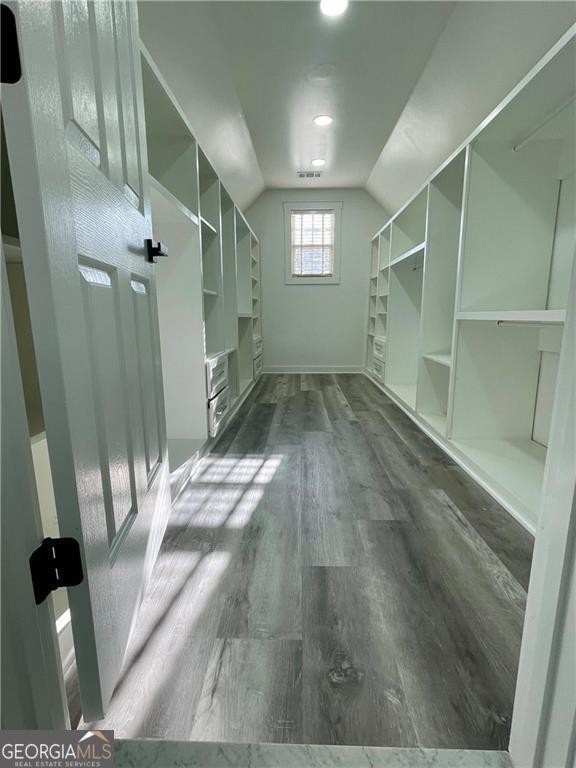 spacious closet with lofted ceiling and dark wood finished floors