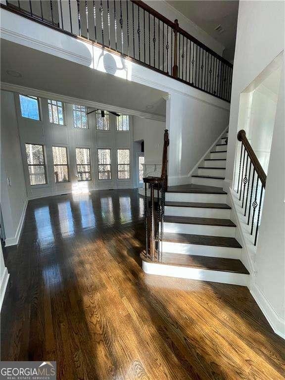 staircase featuring a high ceiling, baseboards, and wood finished floors