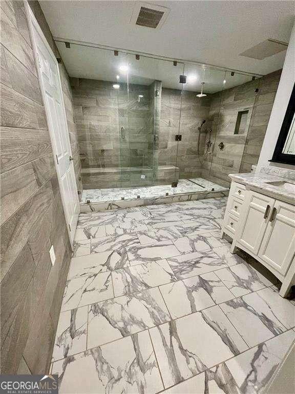 bathroom with marble finish floor, a shower stall, and vanity