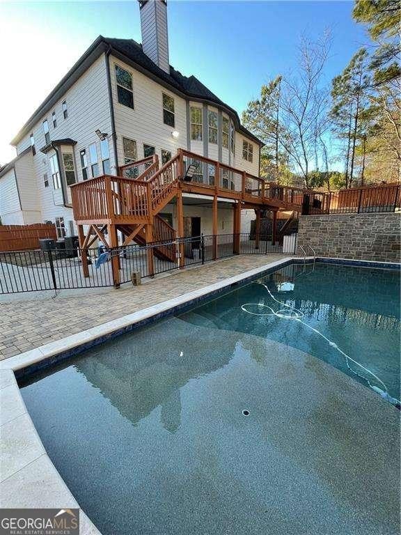 view of pool featuring stairs, a patio, a wooden deck, and fence