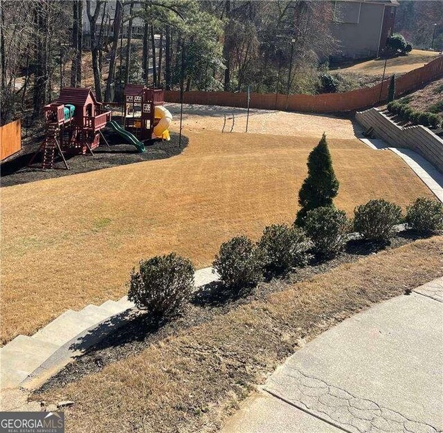 view of yard featuring playground community and fence